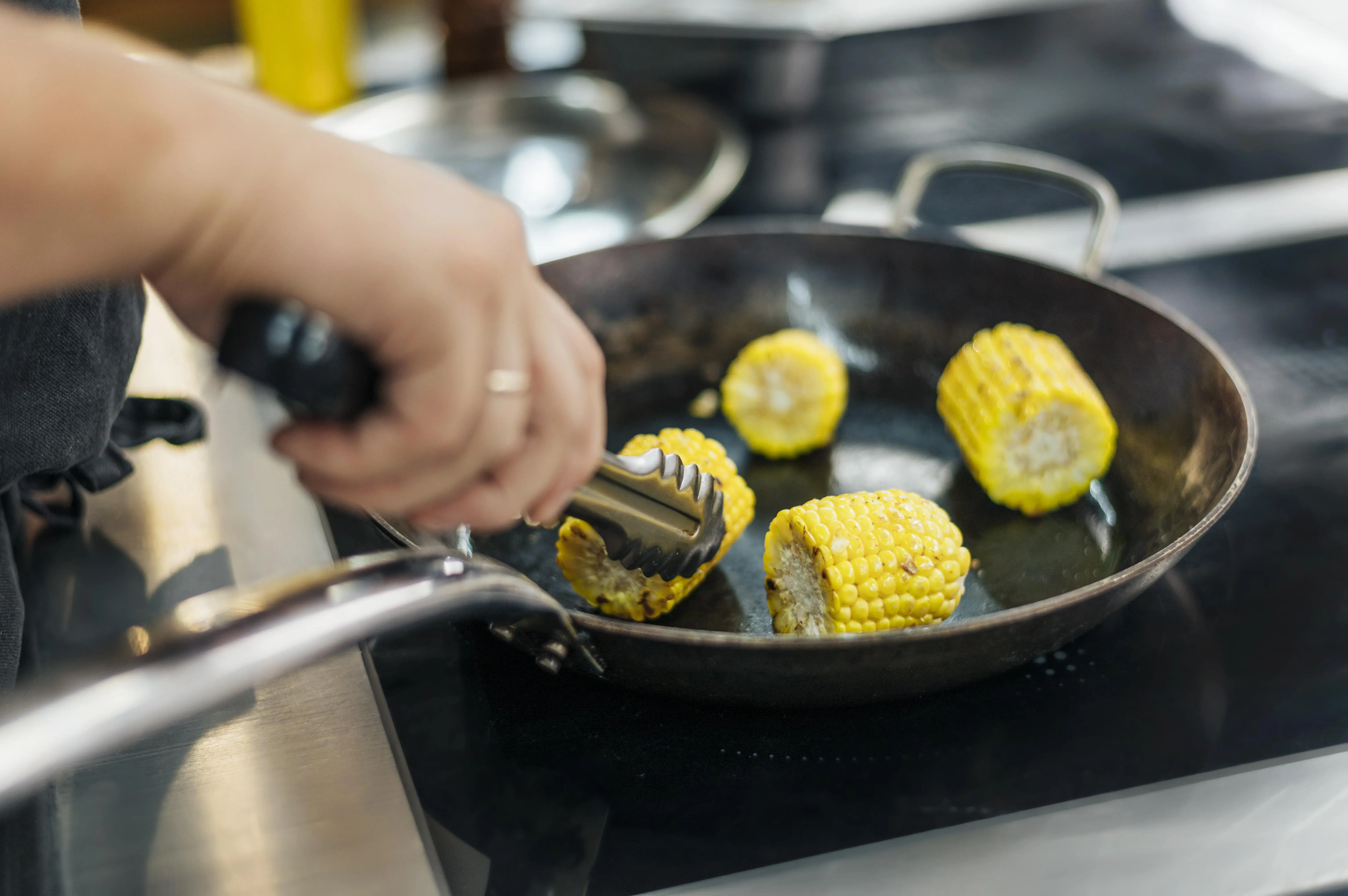 male-chef-frying-corn-cobs-pan.webp